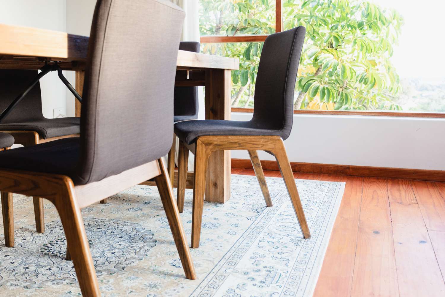 Tapete de cor clara sob a mesa da sala de jantar com cadeiras de jantar puxadas para fora